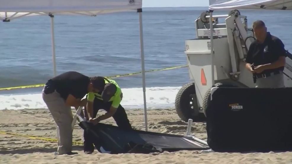 Police Body of woman buried on beach, with arm above sand KABB